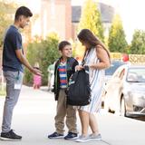Perkins School For The Blind Photo - A student smiles broadly at his mother as a teacher offers his right hand for a low five.